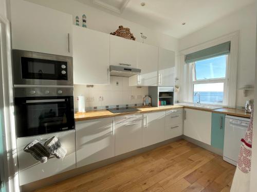 une cuisine avec des placards blancs et une grande fenêtre dans l'établissement Sandy Toes - awesome beach view and access, à Ventnor