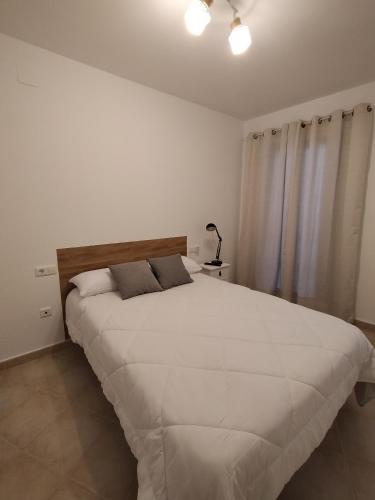 een groot wit bed in een witte slaapkamer met gordijnen bij Estudio 42 in Ayamonte