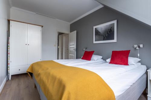 a bedroom with a large white bed with red pillows at Villa Svolvær in Svolvær