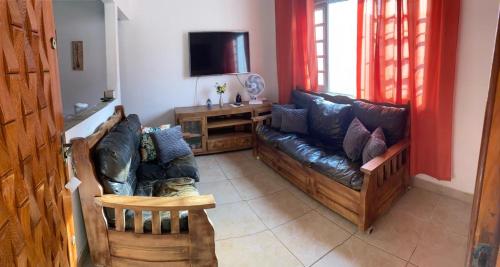 salon z kanapą i telewizorem w obiekcie Casa do lado da praia, 100 metros da praia. w mieście Mongaguá