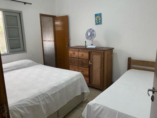 um quarto com 2 camas e uma cómoda com uma ventoinha em Casa do lado da praia, 100 metros da praia. em Mongaguá