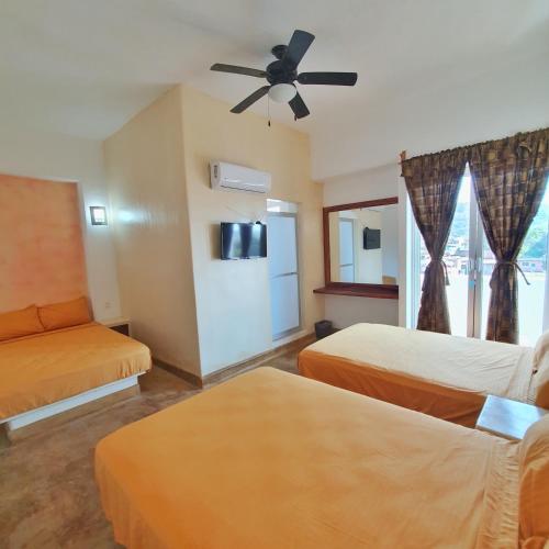ein Hotelzimmer mit zwei Betten und einem Deckenventilator in der Unterkunft Hotel Ixtazihua JP in Zihuatanejo