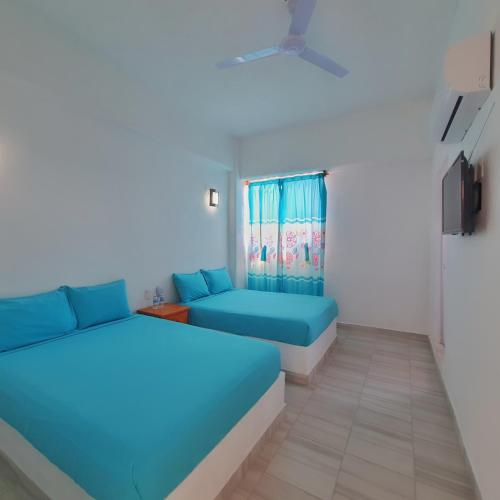 ein Zimmer mit zwei blauen Betten und einem Fenster in der Unterkunft Hotel Ixtazihua JP in Zihuatanejo
