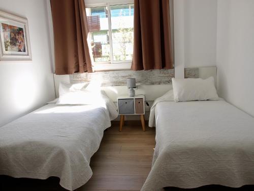 2 łóżka pojedyncze w pokoju z oknem w obiekcie Dalt Vila Salou Deluxe w Salou
