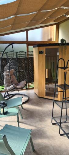 a porch with chairs and a swing on a patio at Gîte 4 étoiles La Belle Eau Calme in Futeau
