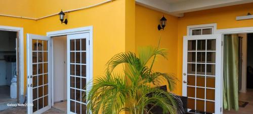 a yellow house with white doors and a plant at Faith's Villa Tobago in Diamond