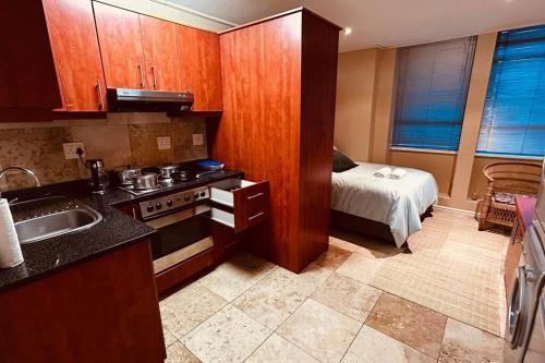 a kitchen with a sink and a bed in a room at Studio Apartment Paarl Central in Paarl