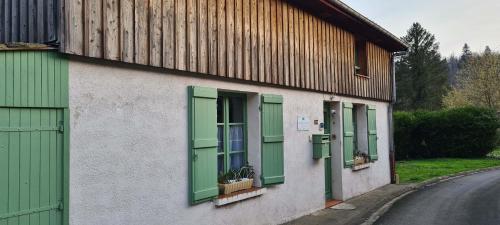 a building with green shuttered windows and a street at Gîte 4 étoiles La Belle Eau Calme in Futeau