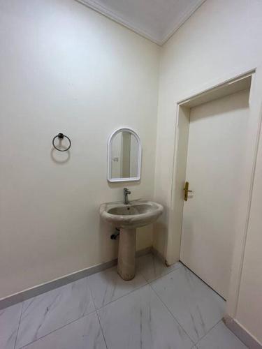 La salle de bains blanche est pourvue d'un lavabo et d'un miroir. dans l'établissement شقة غرفتين ومطبخ Apartment, à Al Rass