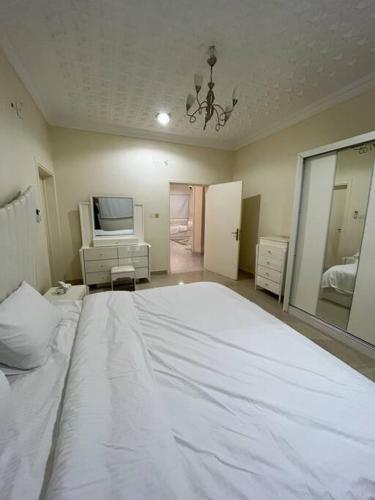 - une chambre avec un grand lit blanc et une télévision dans l'établissement شقة غرفتين ومطبخ Apartment, à Al Rass