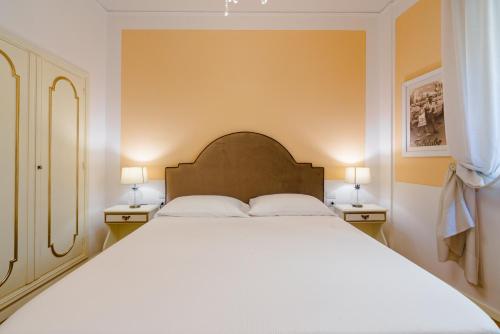 een slaapkamer met een groot wit bed met 2 lampen bij Ponte Vecchio Escape Suite in Florence