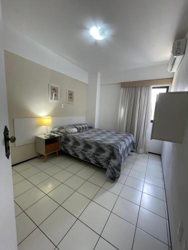 a bedroom with a bed and a table and a window at Flat Biarritz Próximo a Praia - Fonseca Imóveis in São Luís