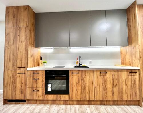 una cucina con armadi in legno e ripiani bianchi di Modern Apartment a Cracovia