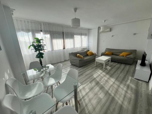 sala de estar con sofá, mesa y sillas en H&H Apartamento Azucena en Granada