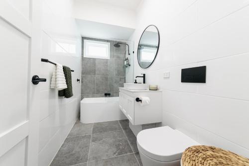 a white bathroom with a toilet and a sink at Urban Getaway Bardon Luxe 3 bed 2 bath and pool in Brisbane