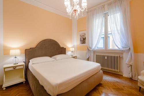 een slaapkamer met een groot wit bed en een kroonluchter bij Ponte Vecchio Escape Suite in Florence