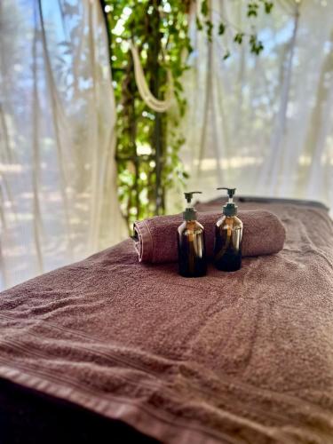 two towels and two perfume bottles sitting on a bed at Domaine Plan des Devens in Roussillon