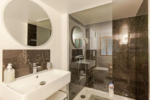 ein Bad mit einem Waschbecken, einem Spiegel und einer Dusche in der Unterkunft L'Ermitage in Rambouillet