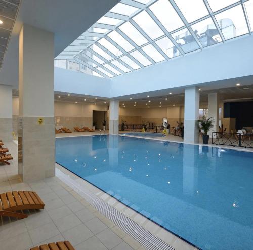 a large swimming pool with a skylight in a building at Luxury condos on 18th, 5th and 3rd floor, with pool, fitness, parking included in Skopje