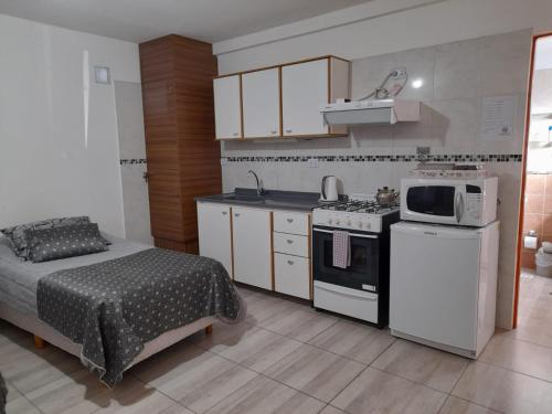 a bedroom with a bed and a kitchen with a microwave at Monseñor Fagnano 592 "6" in Ushuaia