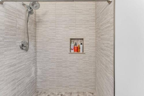 y baño con ducha y pared de azulejos blancos. en Cozy Rancher minutes from Highway, en Reisterstown