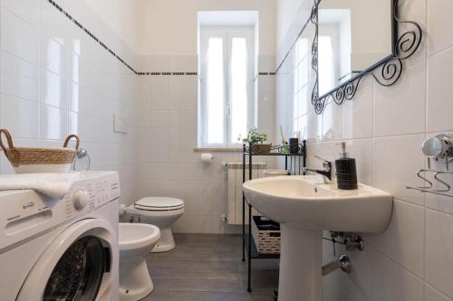 een witte badkamer met een wasmachine en een wastafel bij La Casa di Zoe in Tivoli Terme