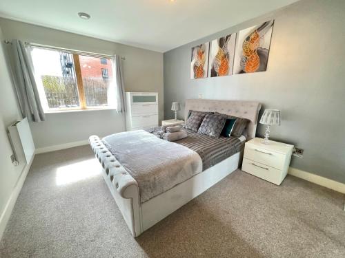a bedroom with a large bed and a window at Bright & Spacious-Secured flat near slough station in Slough