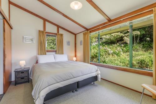 a bedroom with a bed and a large window at Finlay Waterfront - Waikawa Holiday Home in Picton