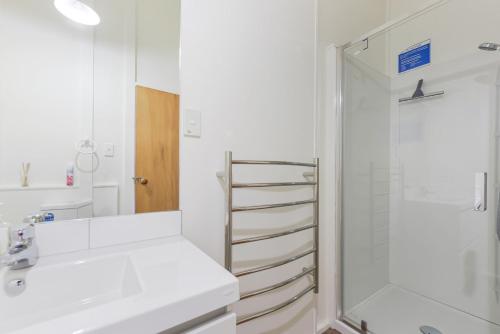 a white bathroom with a sink and a shower at Finlay Waterfront - Waikawa Holiday Home in Picton