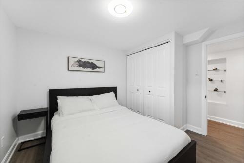a white bedroom with a bed and a closet at Modern 3BR Suites in Ottawa