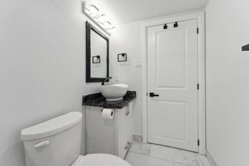 a white bathroom with a toilet and a sink at Modern 3BR Suites in Ottawa