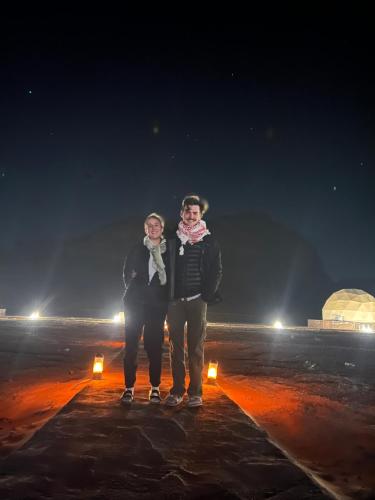 dos personas de pie en la nieve por la noche en Xperience golden rum camp en Wadi Rum
