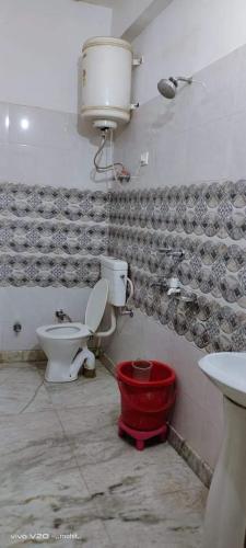 La salle de bains est pourvue de toilettes, d'un lavabo et d'un seau rouge. dans l'établissement Vidya hotel, à Katra