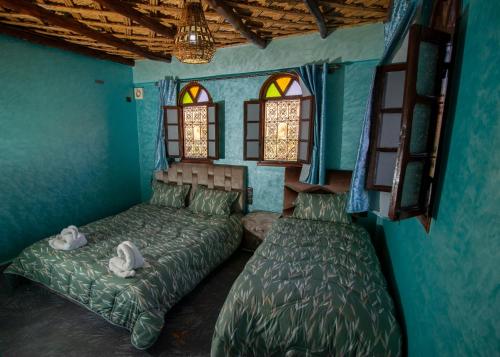 a bedroom with two beds and two windows at Palma Ziz in Aït Athmane
