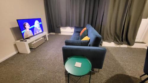 a living room with a blue couch and a tv at Garland Modern Spacious Flat, London in London