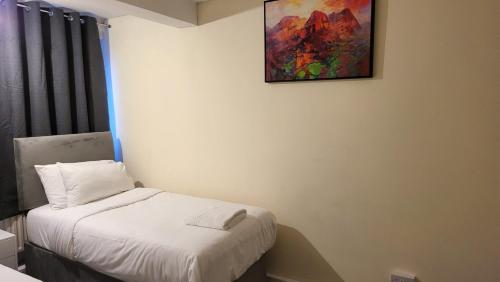 uma pequena cama num quarto com uma pintura na parede em Garland Modern Spacious Flat, London em Londres