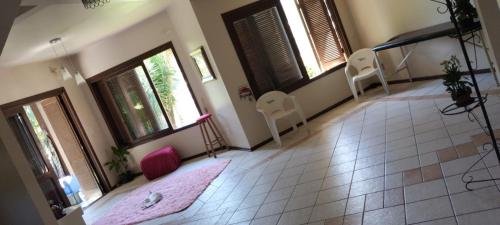 Habitación con 2 sillas, 2 ventanas y alfombra rosa. en Hostel de Gaia, en Santa Cruz do Sul
