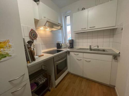 a small kitchen with white cabinets and a sink at barrierefreie Ferienwohnung am Lübecker Hof in Stockelsdorf