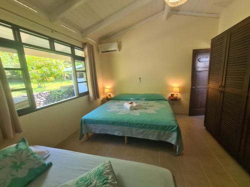 1 dormitorio con 2 camas y ventana en Villa MONOIHERE, en Mahina