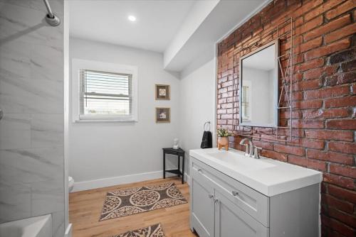 a bathroom with a white sink and a brick wall at Classic Pittsburgh 4 Square - Easy Access to Town and Airport in Pittsburgh