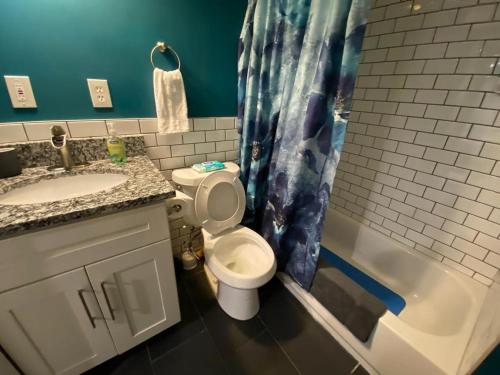 een badkamer met een toilet, een wastafel en een bad bij Jasmine in CWE in Tower Grove