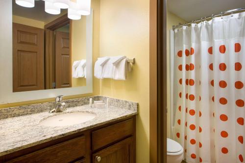 a bathroom with a sink and a toilet and a mirror at Sonesta Simply Suites Phoenix Scottsdale in Scottsdale