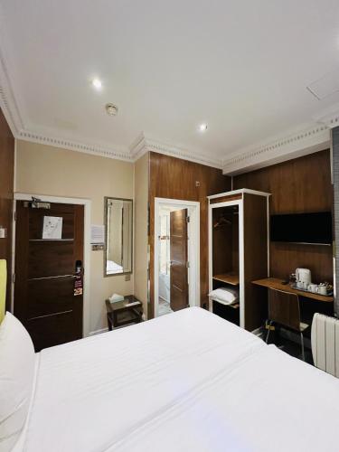 a bedroom with a large white bed and a desk at Cheshire Hotel Central London in London