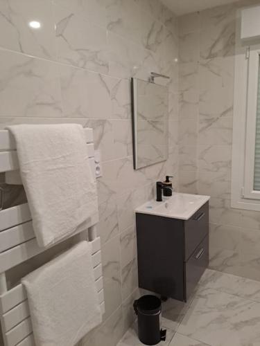 une salle de bain blanche avec un lavabo et un miroir dans l'établissement 24h course/Moto/ Oasis / Antares, au Mans