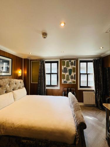 a bedroom with a large bed and two windows at Cheshire Hotel Central London in London