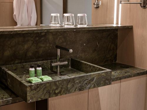 a sink in a bathroom with three wine glasses at Pulso Hotel Faria Lima in Sao Paulo