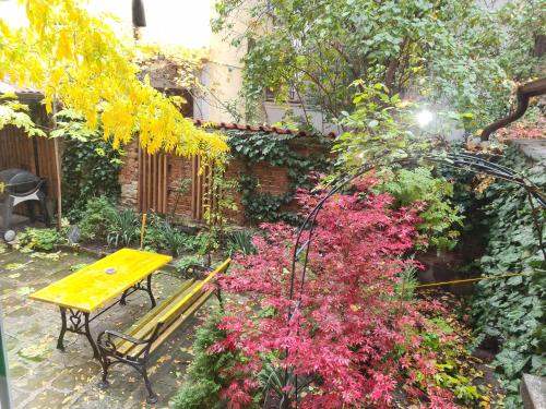 a yellow bench in a garden with pink flowers at ArtE Vitosha Blvd in Sofia