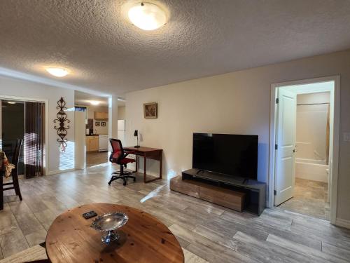 a living room with a flat screen tv and a table at Peaceful suite near the lake in Victoria