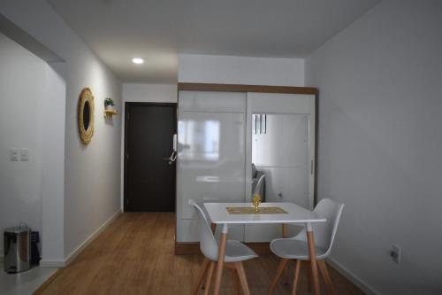 une cuisine avec une table et des chaises blanches ainsi qu'une porte dans l'établissement Hermoso apartamento a 150 metros de la rambla, à Montevideo