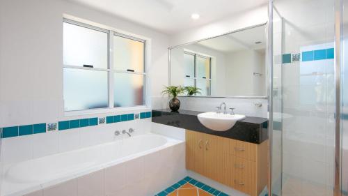 ein Badezimmer mit einem Waschbecken, einer Badewanne und einem Spiegel in der Unterkunft Riverview Apartment 1 Block 1 in Iluka